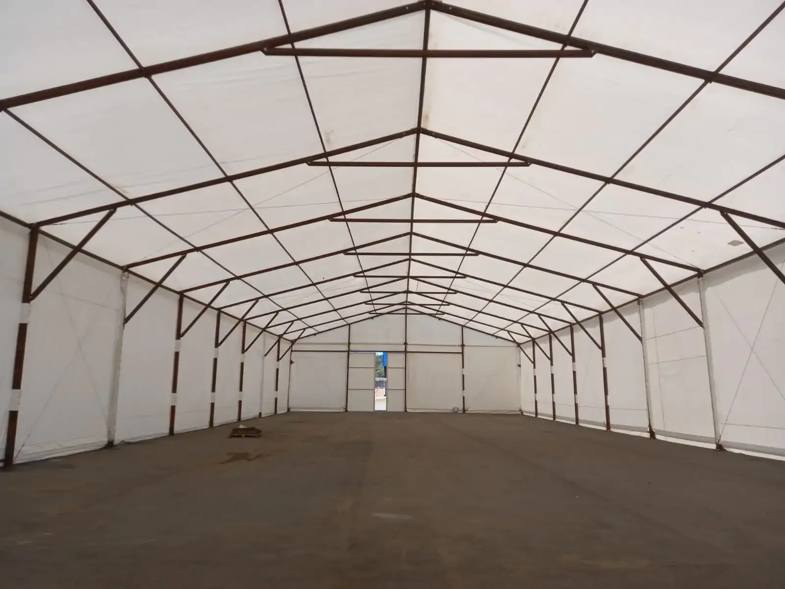 Interior de galpão de lona com estrutura metálica aparente e grande vão